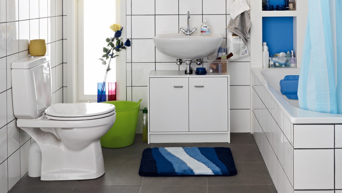 Cluttered bathroom seen before the renovation, with floor-standing toilet and exposed cistern